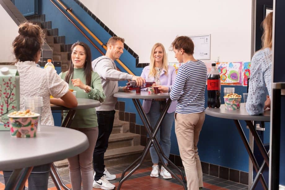 Mensen die genieten van een informele netwerkborrel op kantoor, met hapjes en drankjes.